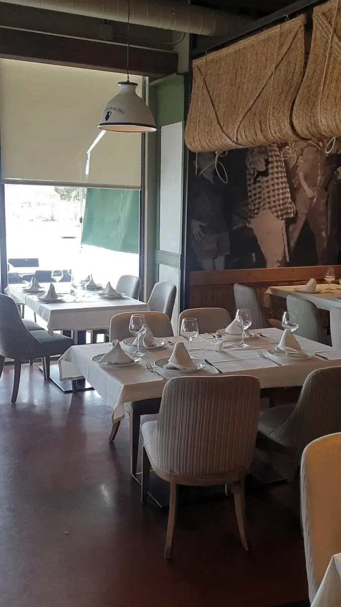 Sala del restaurante con manteles blancos, espartos colgados y mural de vendimia